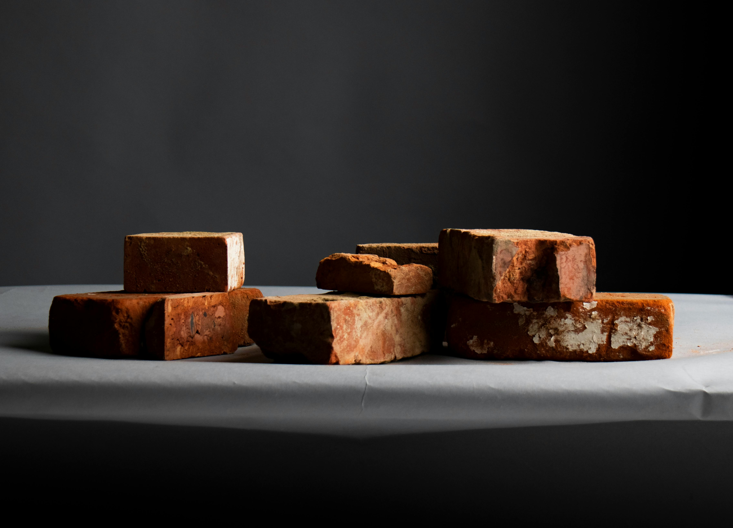 Close-up of stacked red bricks on a dark neutral background, texture and material study.