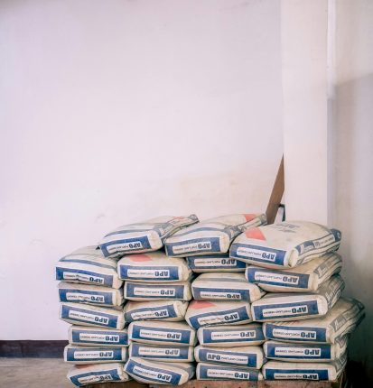 A stack of bags of cement neatly arranged in an indoor warehouse environment.